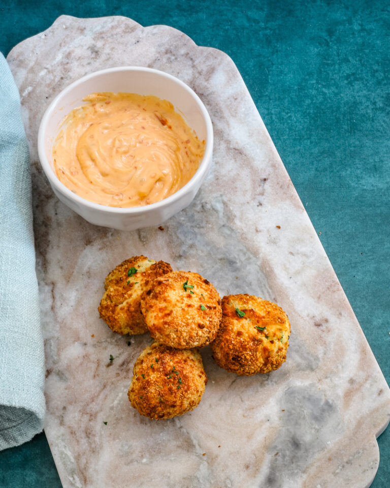 A plate of homemade air fryer potato croquettes made with leftover mashed potatoes, cheese, and herbs, and a dip on the side