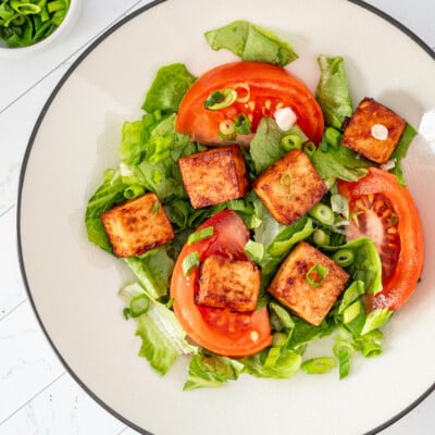 Air fried tofu cubes on lettuce with tomatoes and green onions.