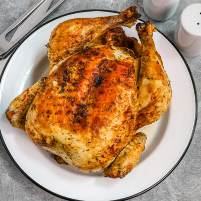 Whole air fryer roasted chicken on a plate.