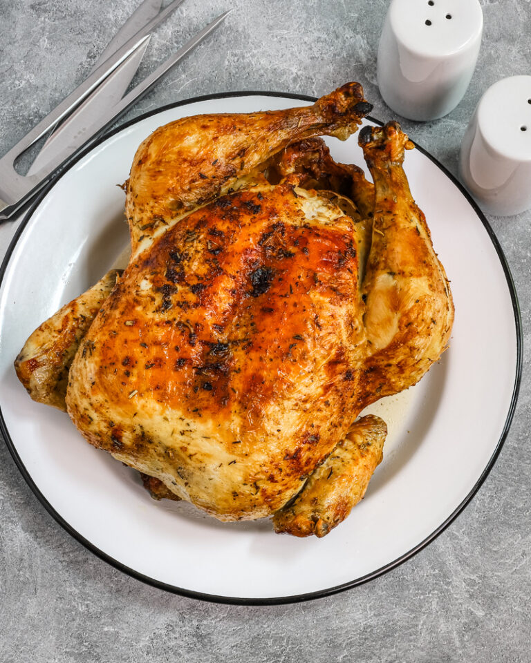 Whole air fryer roasted chicken on a plate.