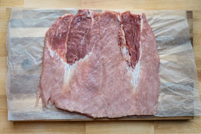 A butterflied pork loin roast on wax paper.