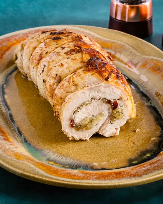 A pork loin roast stuffed with apple and dried cranberries on a Kentucky pottery platter.
