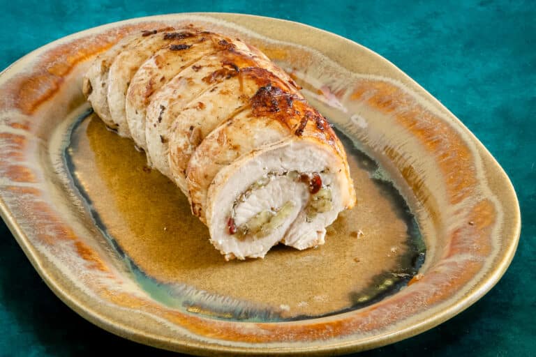 The rolled and stuffed pork loin on a pottery platter.