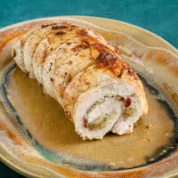 Rolled pork loin on a pottery platter, stuffed with apples and cranberries.