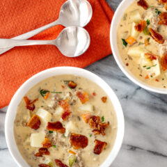 Bacon cheeseburger soup in bowls with an orange napkin.
