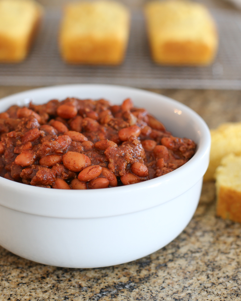 Beefy beans in a bowl with cornbread in the background.
