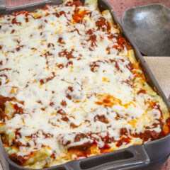 Baked ziti in a baking dish with serving spoon.