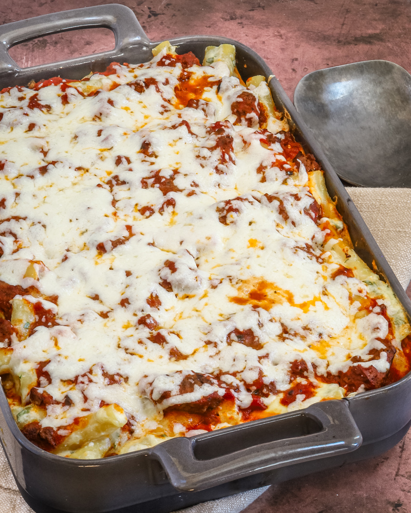 Baked ziti in a baking dish with serving spoon.