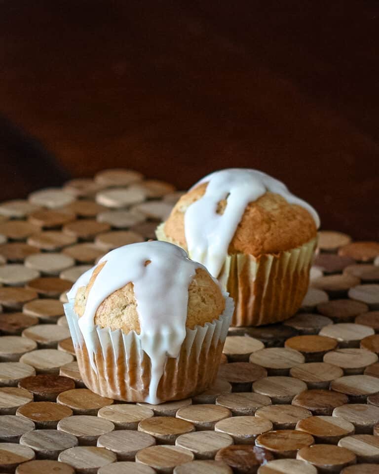 Two banana cupcakes with drizzled icing.
