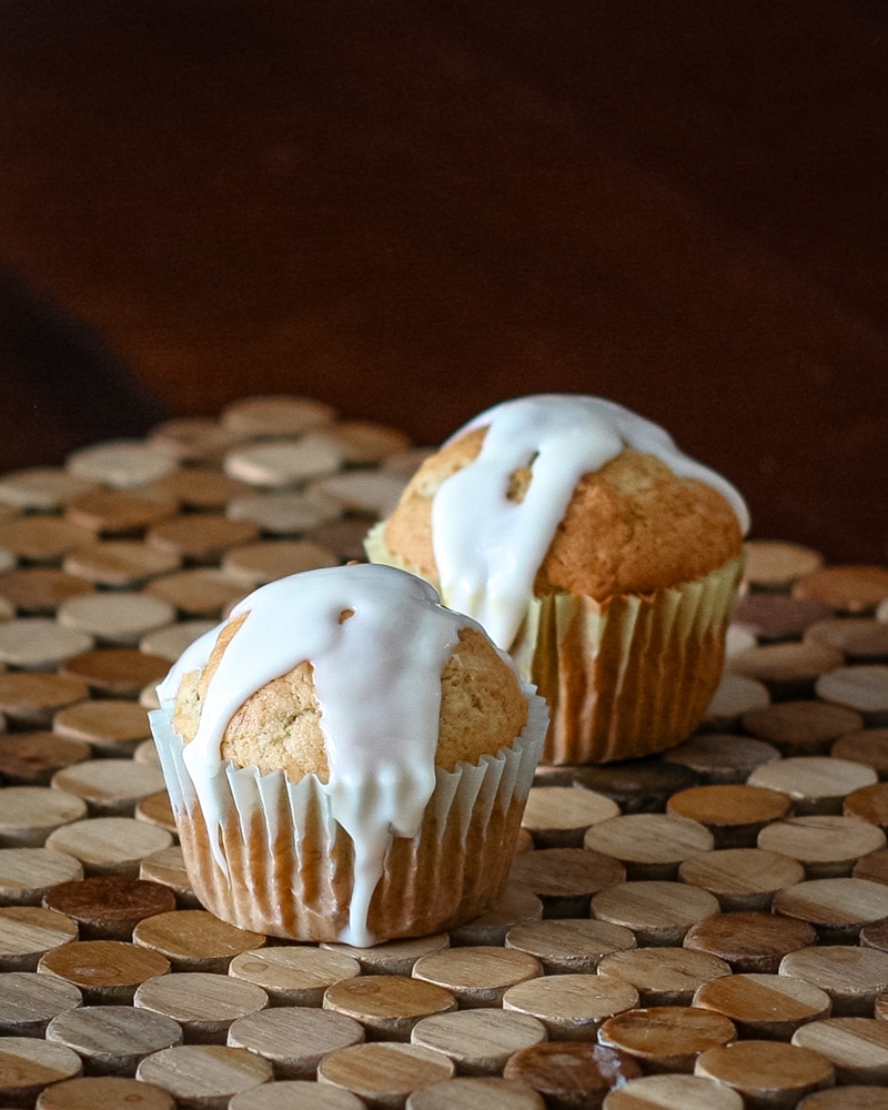 Two banana cupcakes with drizzled icing.