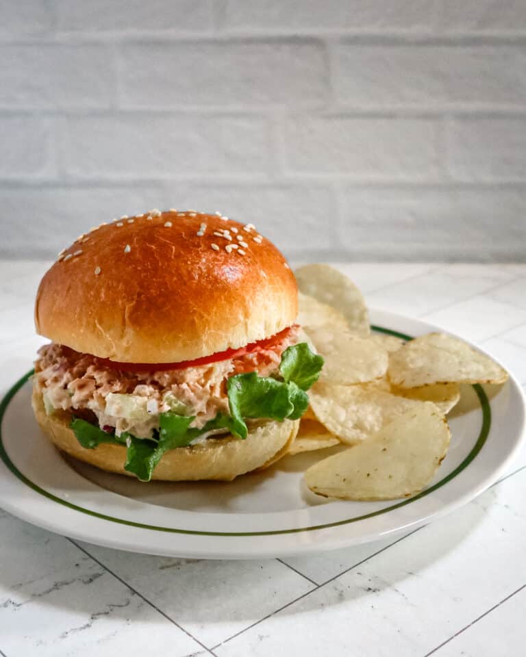 A sandwich made with homemade brioche buns with chips on the side.