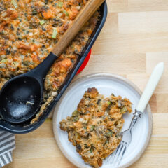 A serving of sausage brioche dressing with the baking dish beside it.
