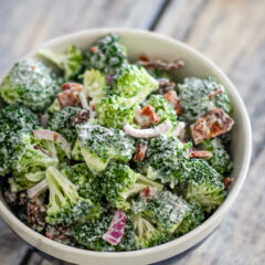 Creamy broccoli salad with red onion and bacon bits.
