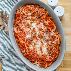 A serving bowl with bucatini all'Amatriciana topped with grated pecorino Romano and extra guanciale.