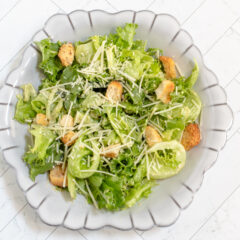 A bowl of Caesar salad with croutons and parmesan cheese.