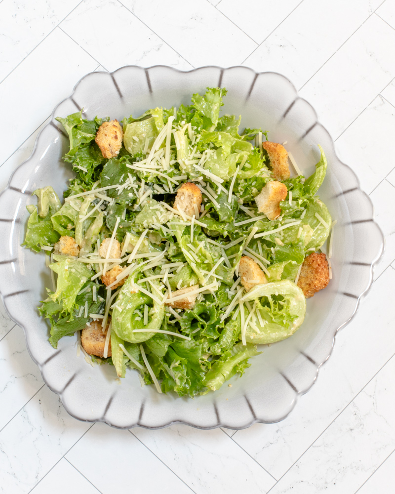 A bowl of Caesar salad with croutons and parmesan cheese.