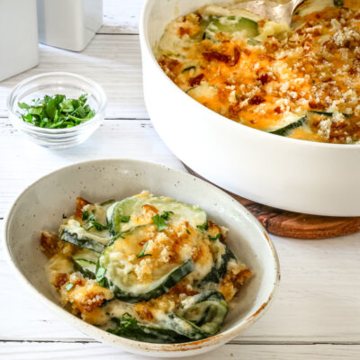 Zucchini casserole serving with the baking dish in the background.