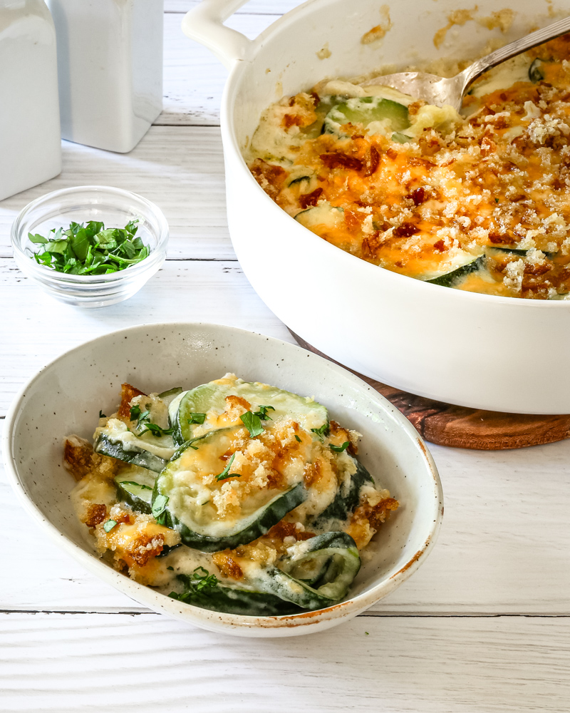 Zucchini casserole serving with the baking dish in the background.