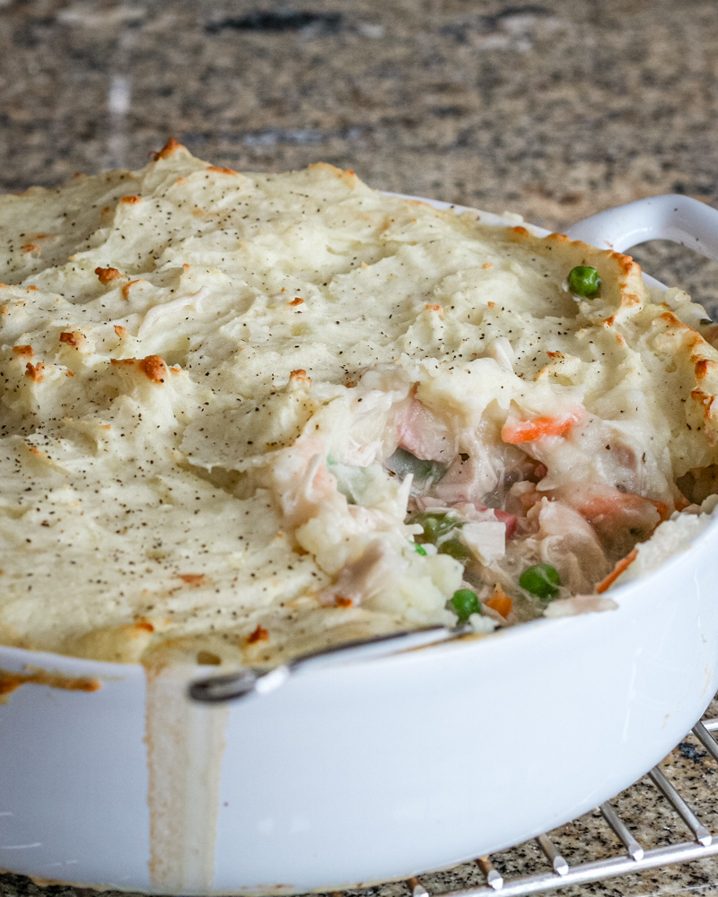 A chicken and ham pie in a baking dish with mashed potato topping.