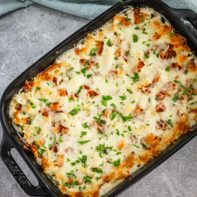 A baking dish with chicken bacon ranch casserole topped with parsley garnish.
