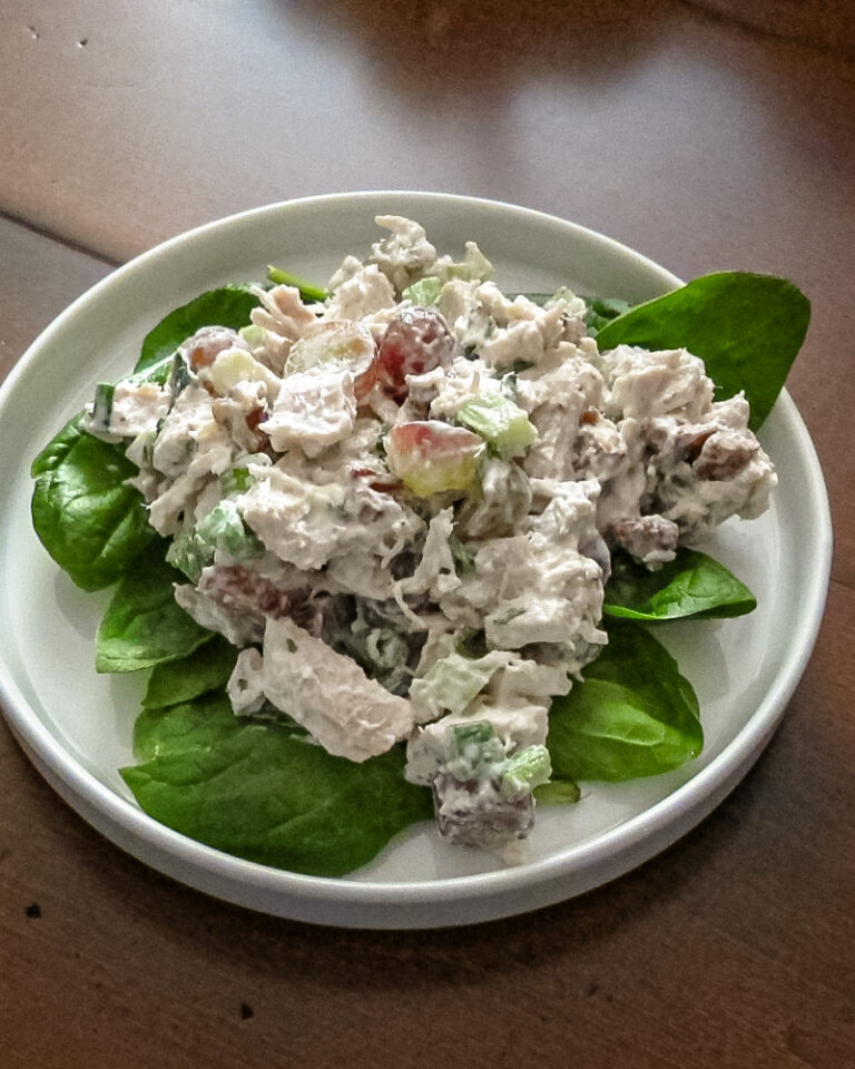 A lettuce-lined plate of chicken salad with grapes.