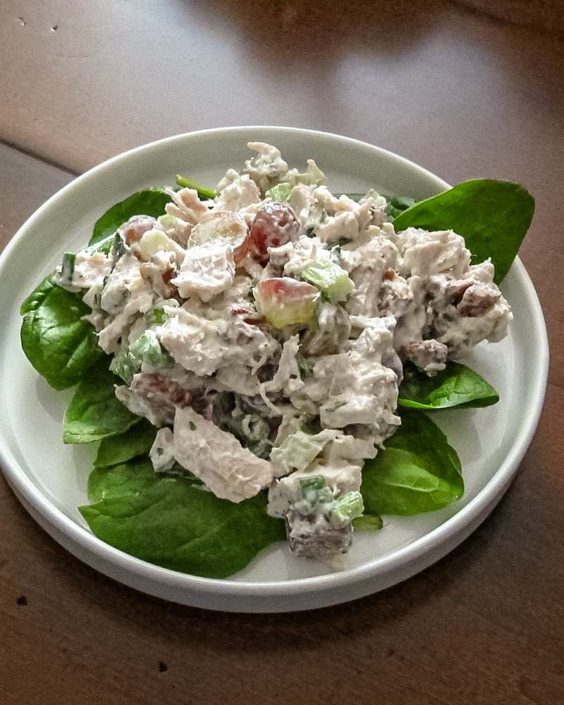 A lettuce-lined plate of chicken salad with grapes.