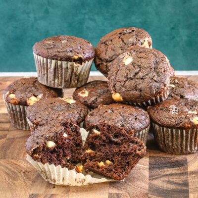 Several chocolate zucchini muffins with one split.