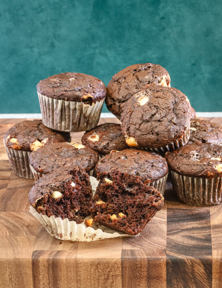 Several chocolate zucchini muffins with one split.