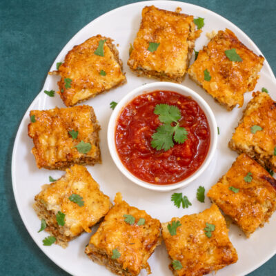 Chorizo sausage quiche squares on a platter with salsa.