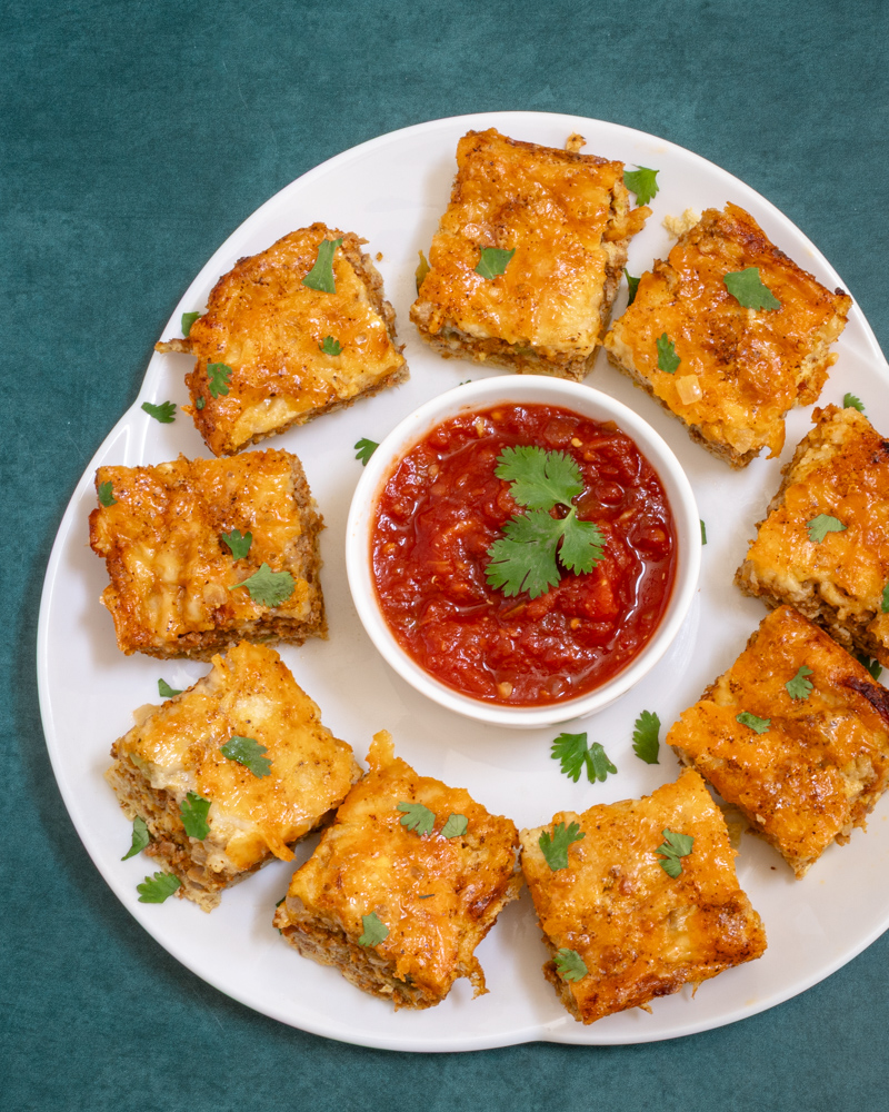 Chorizo sausage quiche squares on a platter with salsa.