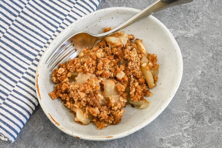 Apple crisp in a dessert dish with fork.