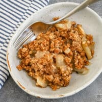 Apple crisp in a dessert dish with a fork on the side.
