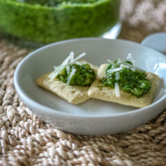 Classic pesto on an appetizer plate, served on crackers with parmesan cheese.