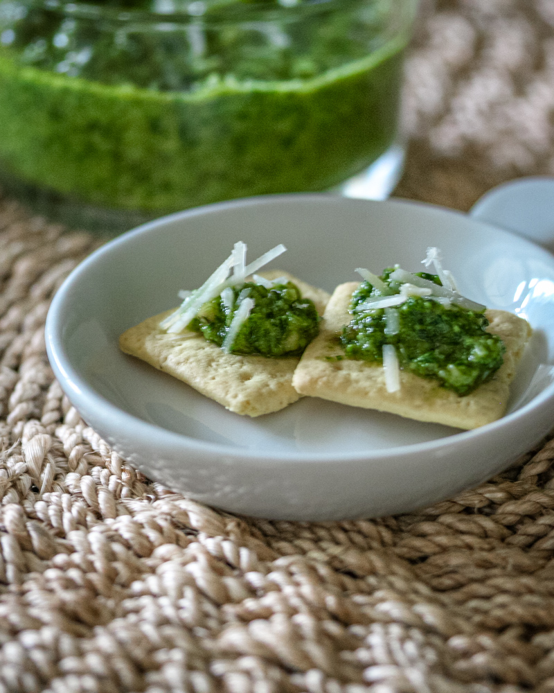 Classic pesto on an appetizer plate, served on crackers with parmesan cheese.