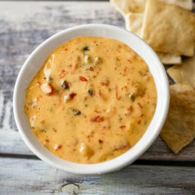 A bowl of Rotel dip with crackers beside it.