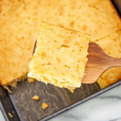 Overhead shot of a moist cornbread casserole being removed from the baking pan.