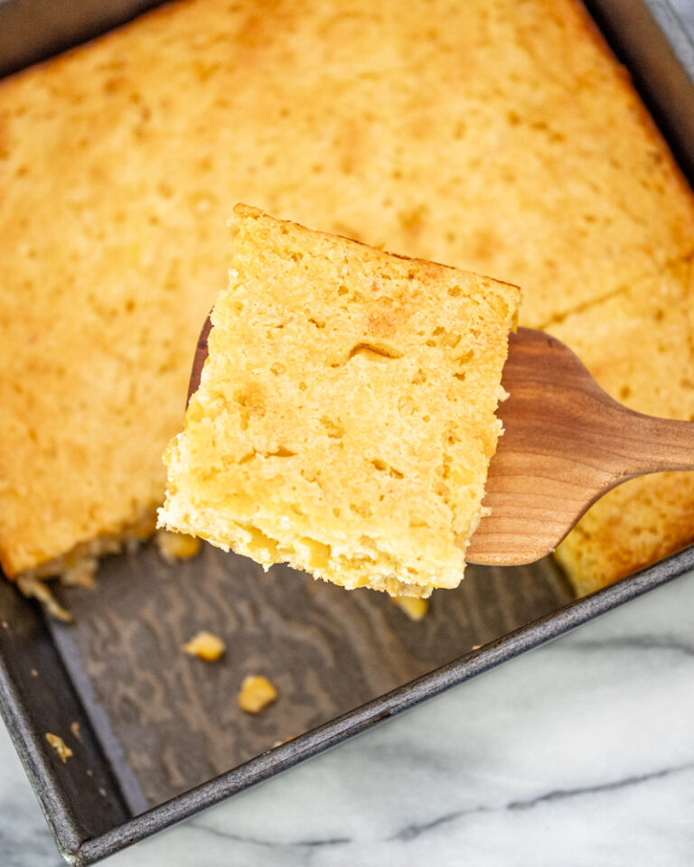 Overhead shot of a moist cornbread casserole being removed from the baking pan.