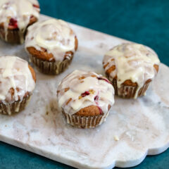 Glazed cranberry orange muffins shown on a marble slab .