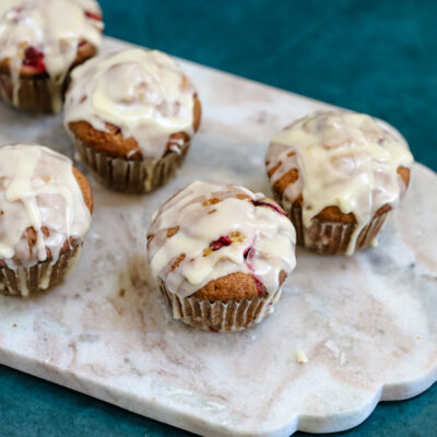 Glazed cranberry orange muffins shown on a marble slab .