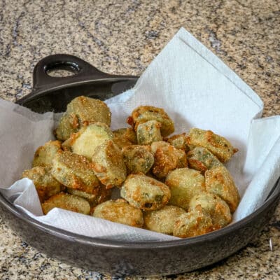 Fried pickles in a serving dish on paper towels.