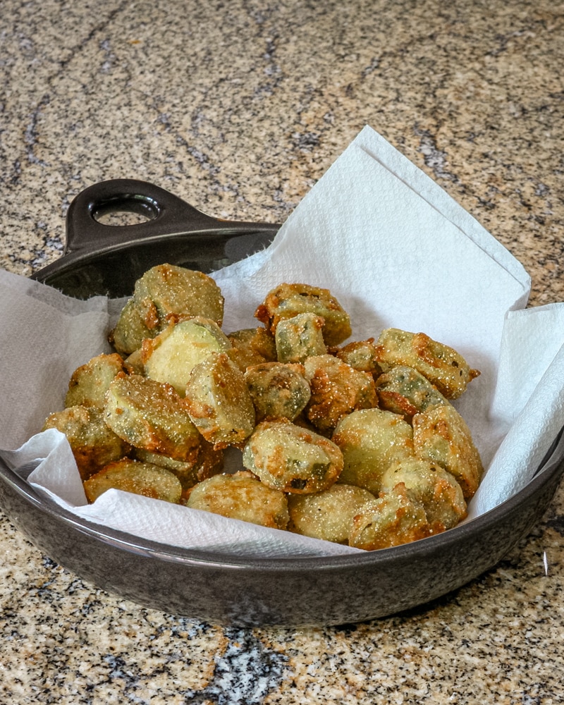 Fried pickles in a serving dish on paper towels.