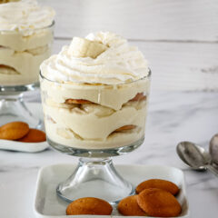 Trifle dessert glasses with banana pudding topped with whipped cream.
