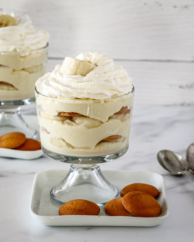 Trifle dessert glasses with banana pudding topped with whipped cream.