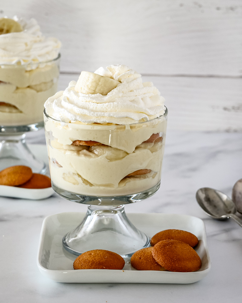 Trifle dessert glasses with banana pudding topped with whipped cream.