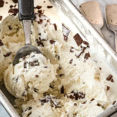 A loaf pan with no churn ice cream being scooped out, and a couple of ice cream spoons on the right.