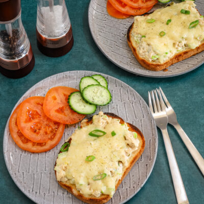 Tuna melt sandwiches, open-faced, with sliced tomatoes and cukes on the side.