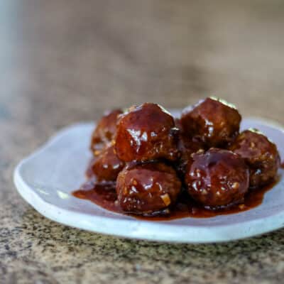 A serving plate with grape jelly meatballs.