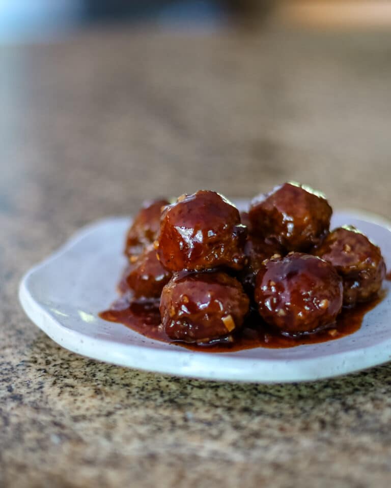 A serving plate with grape jelly meatballs.