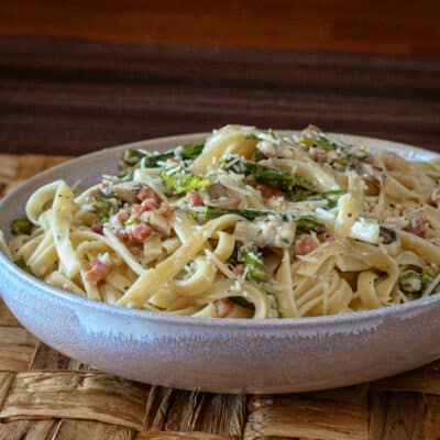 Creamy fettuccine with ham and asparagus in a wide bowl.