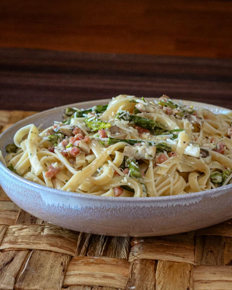 Creamy fettuccine with ham and asparagus in a wide bowl.